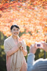 Obraz premium 紅葉を持ち微笑む女性