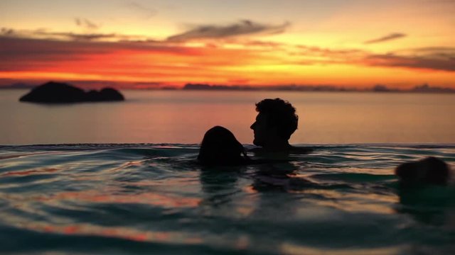 Honeymoon, tourism, luxurious hotel resort concept. Slow-motion romantic couple woman man silhouette contemplating sunset beautiful dawn chinese sea swimming infinity pool merging sea water