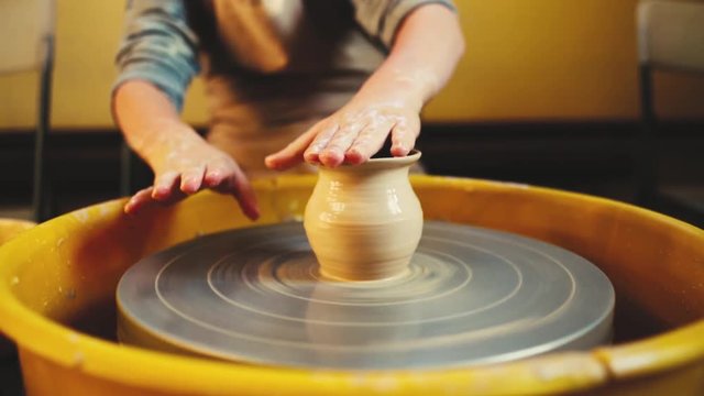 Handcraft Pottery inside. childrens Hands working on pottery wheel, shaping a clay vase. Children Making Pottery In Workshop, potter's wheels in the pottery workshop