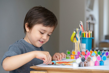 Happy boy having fun painting water colour on paper,Kid holding art brush learning painting and drawing at home,Indoor activities for children on school break, Art for kids concept