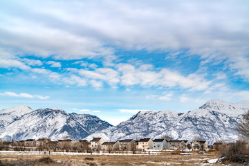 Beautiful blue sky with puffy clouds over homes and mountain in winter