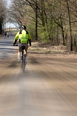 Obraz premium Cyclist rides along the park alley, artistically blurred image, speed lines