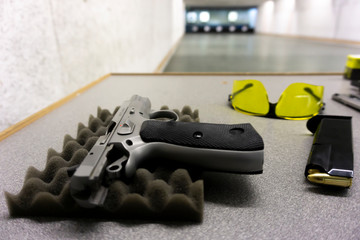 9 mm pistol with magazine and safety goggles on a table on a shooting range