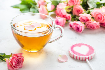 Cup of tea and tender pink roses on a white background