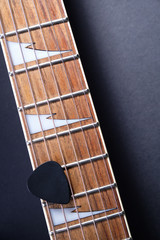 Guitar frets with strings and mediator on dark background