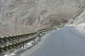 asfaltowa droga z barierką zabezpieczającą biegnąca po górskim zboczu wśród nagich skał w nepalu