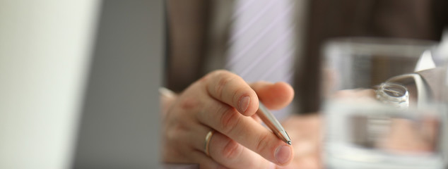 Male arm in suit and tie hold silver pen filling schedule in notepad at office workplace closeup....