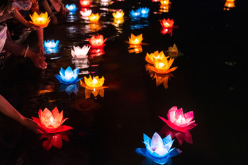 Floating colored lanterns and garlands on river at night on Vesak day for celebrating Buddha's birthday in Eastern culture, that made from paper and candle © Hanoi Photography
