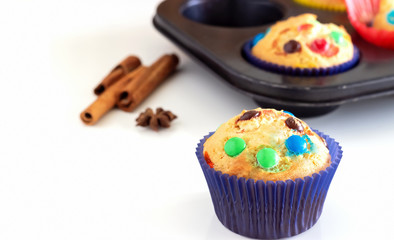 Homemade lemon muffins with colorful chocolate candy in paper case. White background. Selective focus