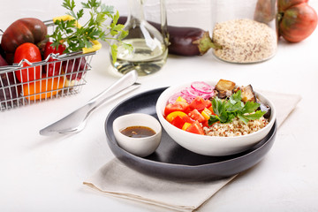 Quinoa salad with roasted eggplant, fresh tomatoes and red onion.   Vegan or vegetarian food. Healthy salad in bowl served on white table.