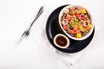 Quinoa salad with roasted eggplant, fresh tomatoes and red onion.   Vegan or vegetarian food. Healthy salad in bowl served on white table. Top view, copy space.