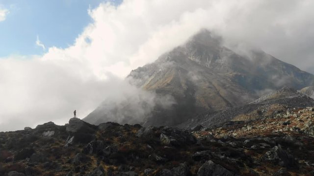 4k aerial side fly with man on rocks in front of a mountain in Langtang Valley in Nepal