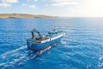 Fishing vessel boat floating in the blue sea along the coast.