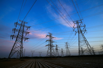 A silhouette of a high voltage tower at sunset