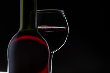 Rose wine. Red wine in bottle with wine glass over dark background. Silhouette