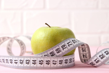 apple and measuring tape on a colored background side view.