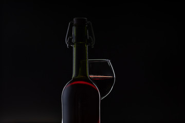 Rose wine. Red wine in bottle with wine glass over dark background. Silhouette