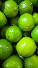 Closeup photo of green limes with GMO lying on counter at store. Closeup texture or pattern of fresh ripe fruits. Beautiful food background