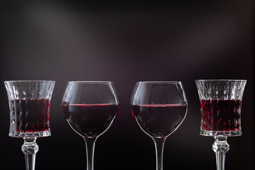 Rose wine. Red wine in four wine glasses over dark background with rays of light