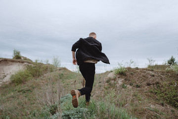 Portrait of a guy running through the mountains in search. Nutrition of confusion, feelings, despair, haste