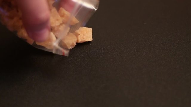 hand pulls out crystalline substances from a plastic bag