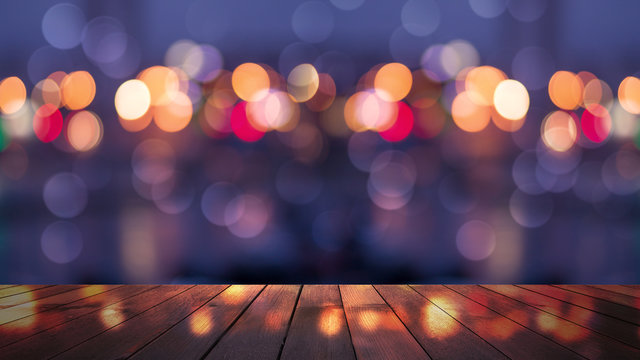 Empty wooden table with blurred cityscape, blurred city lights reflected on wooden background. Empty background template with bokeh