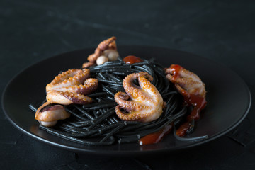 Black pasta with octopus on black background