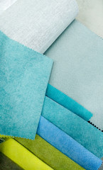 Closeup image of assortment of fabric samples for soft furniture. Blue and green pieces of material. Abstract closeup background