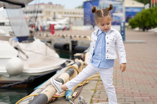 Little girl model on the marina dressed in stylish and fashionable clothes. The kid participates in a photo shoot to advertise children's things