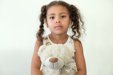 Cute girl with pigtails in white dress with teddy