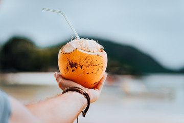 Holding a tropical cocktail in a coconut on a beautiful beach on Mahe island