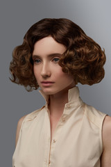 Cropped closeup half-turn view shot of girl with chestnut curly blunt bob hairstyle, wearing...