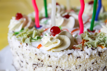 Traditional sweet birthday cake with colorful candles.