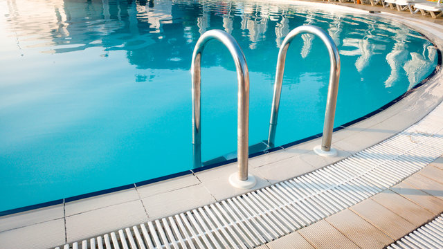 Closeup image of metal handrails on staircase at outdoor swimming pool