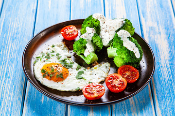 Fried egg with vegetables on wooden table