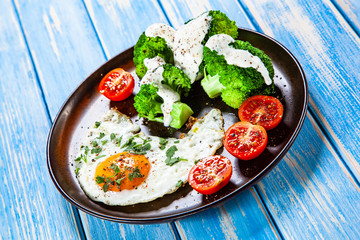 Fried egg with vegetables on wooden table
