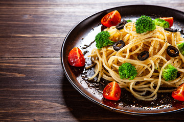 Pasta with herbs and vegetables on wooden background