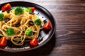 Pasta with herbs and vegetables on wooden background