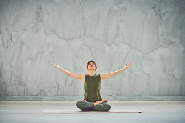 Beutiful woman sitting on the mat in lotus posture.