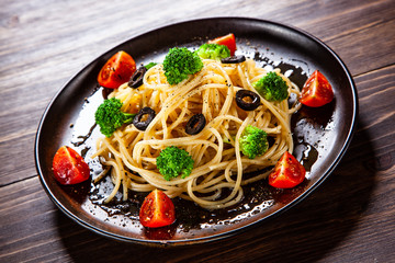 Pasta with herbs and vegetables on wooden background