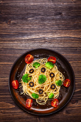 Pasta with herbs and vegetables on wooden background
