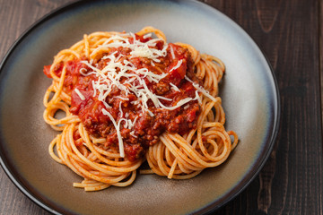 Spaghetti Bolognese sauce or tomato sauce on a dark wooden board, traditional Italian food closeup and top view