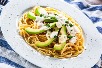 Pasta with avocado on wooden table