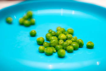 Peas at dinner time on a blue plate