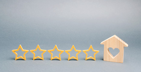Five stars and a wooden house on a gray background. The concept of the best housing, luxury...