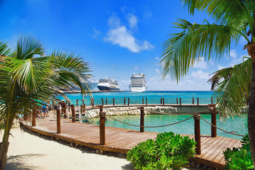 View from beach at tropical resort on cruise ships docked at port 