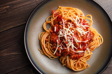 Spaghetti Bolognese sauce or tomato sauce on a dark wooden board, traditional Italian food closeup and top view