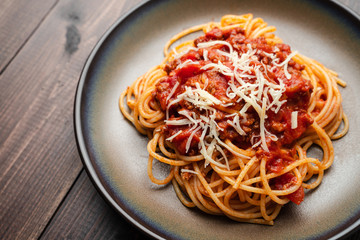 Spaghetti Bolognese sauce or tomato sauce on a dark wooden board, traditional Italian food closeup and top view
