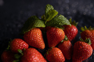 leaf fresh red strawberries macro on black table waterdrops
