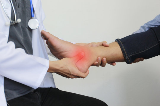 Closeup Of Man Feeling Pain In Her Foot And Doctor The Traumatologist Examines Or Treatment On White Background, Healthy Concept